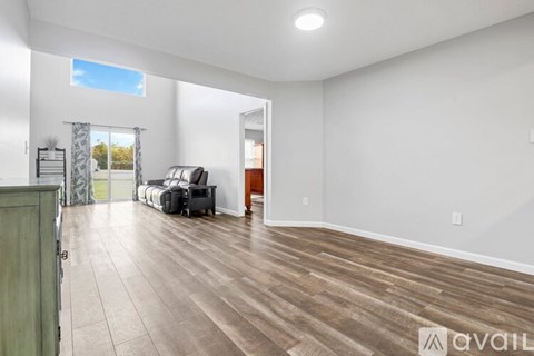 A spacious room with wood flooring and a large window.