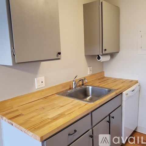 A kitchen with a wooden counter top and a stainless steel sink.