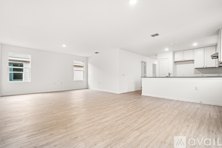 A spacious room with wooden flooring and white walls.