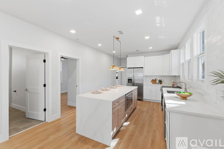 A modern kitchen with white cabinets and a wooden floor.