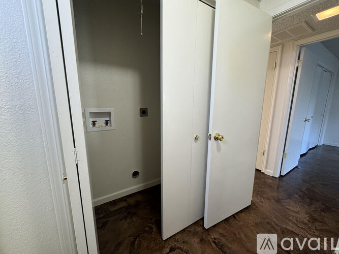 A white door is open to a room with a light switch and socket on the wall.