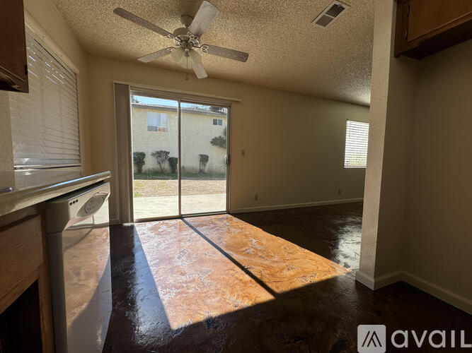 A room with a fan and sliding glass doors leading to a patio.