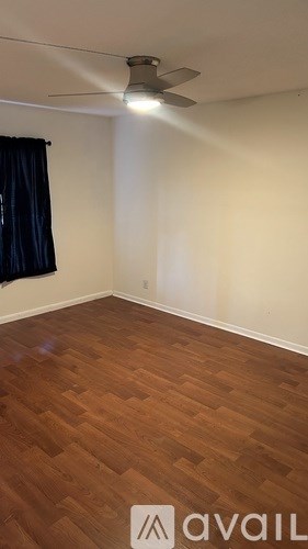 A room with wooden flooring and a ceiling fan.