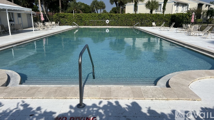 A pool with a diving board and lounge chairs.