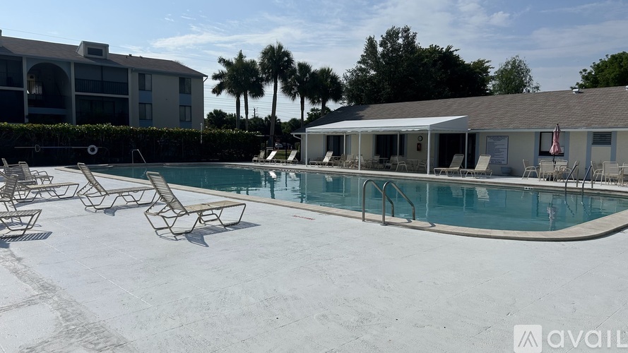 A pool with chairs and a building in the background.