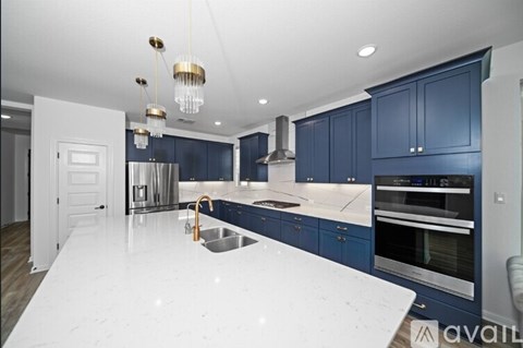 A modern kitchen with dark blue cabinets and a white countertop.
