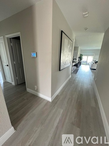 A hallway with a wooden floor and a painting on the wall.