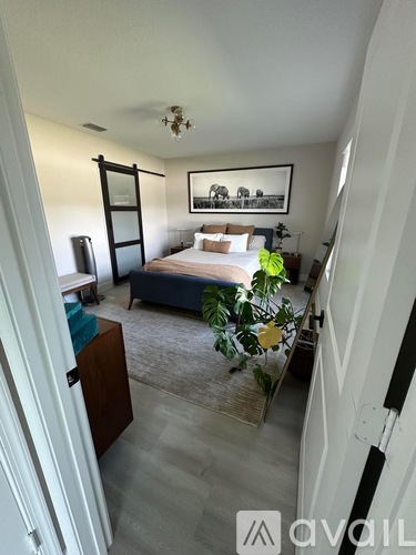 A bedroom with a bed, a dresser, and a painting on the wall.