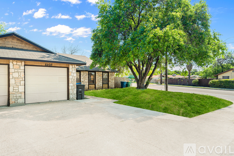 A house with a driveway and a tree in front.