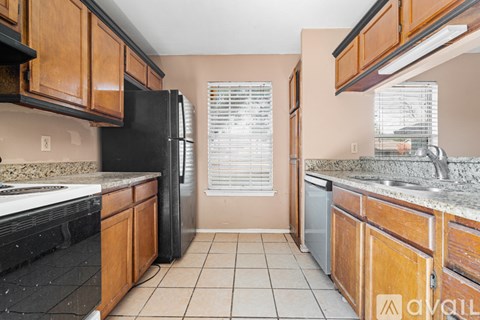A kitchen with black appliances and wooden cabinets.
