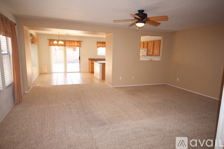 A living room with a carpeted floor and a ceiling fan.