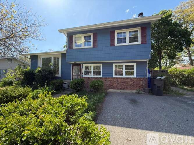 A blue house with a gravel driveway in front.
