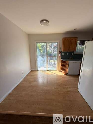 A room with wooden flooring and a white refrigerator.