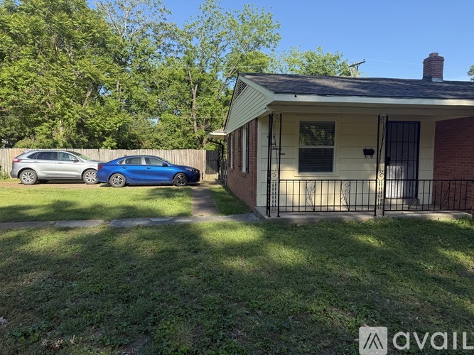 A blue car is parked in front of a house with a white garage door.