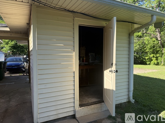A small white shed with a door open to the interior.