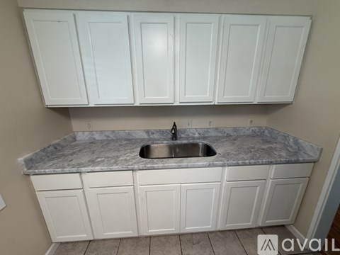 A kitchen with white cabinets and a marble countertop.