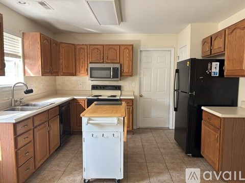 A kitchen with wooden cabinets and a black refrigerator.