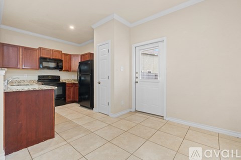 A kitchen with a black refrigerator and wooden cabinets.