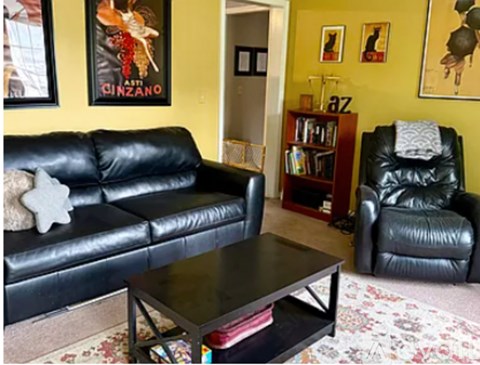 A living room with a black leather couch and a coffee table.