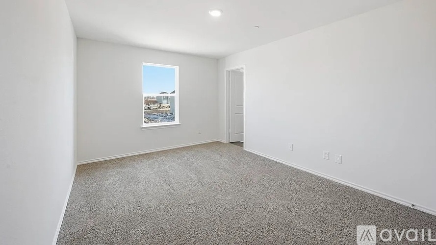 Empty room with a window showing a view of a building and a car.