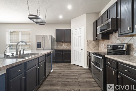 A kitchen with black cabinets and a white door.