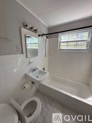 A white bathroom with a toilet, sink, and bathtub.