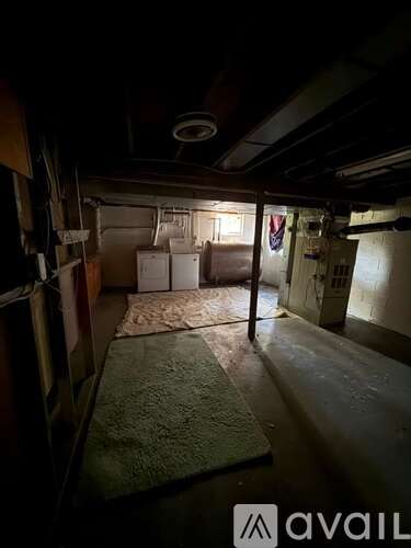 A dark room with a rug on the floor and a fan on the ceiling.