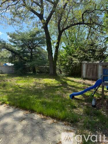 A playground with a blue slide and a tree in the background.
