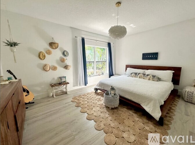 A bedroom with a bed, guitar, and a rug on the floor.