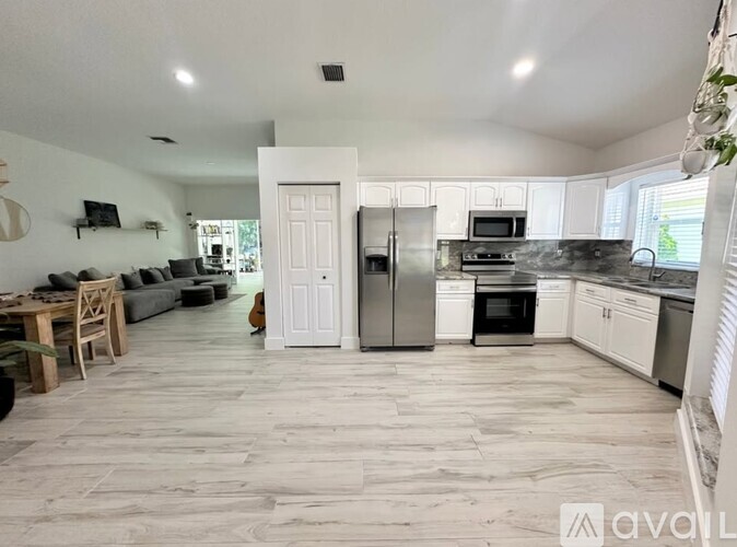 A spacious kitchen and living room with white appliances and a wooden floor.