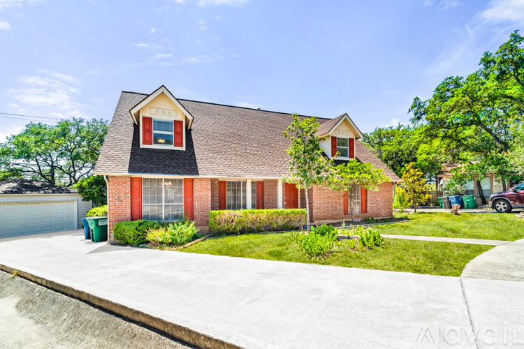 A red brick house with a black roof and a white garage door.
