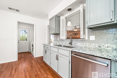 A kitchen with a stainless steel refrigerator and wooden floors.