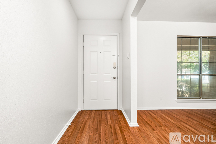 A room with a white door and wooden flooring.