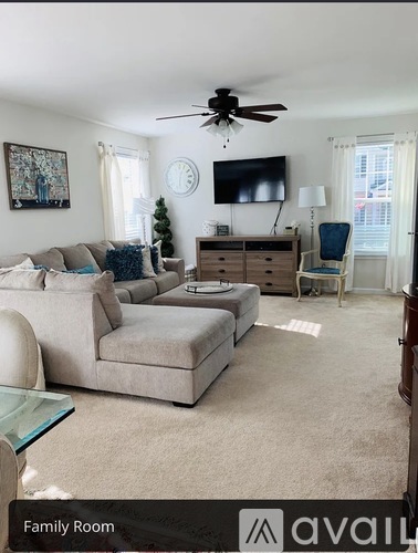 A living room with a grey couch, a white chair, and a television on the wall.