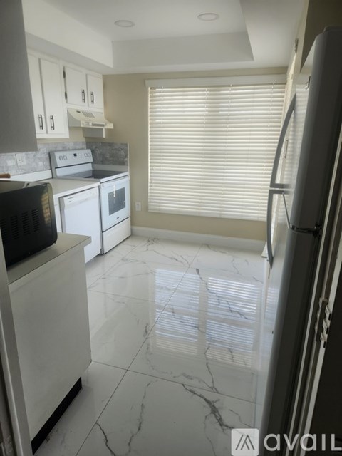 A kitchen with white appliances and marble flooring.