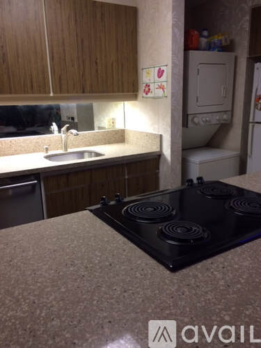 A kitchen with a black stove top and wooden cabinets.