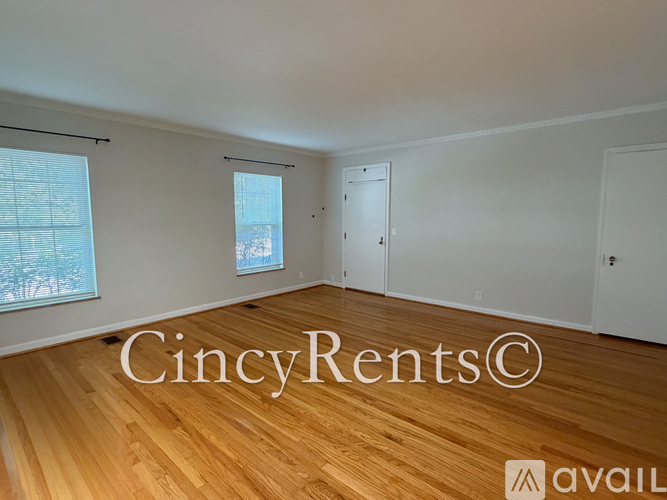 A room with wooden flooring and white walls, with a window showing a snowy scene outside.