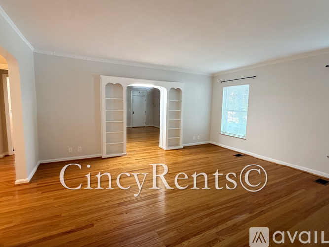 A room with wooden floors and white walls, with a window on the right side.