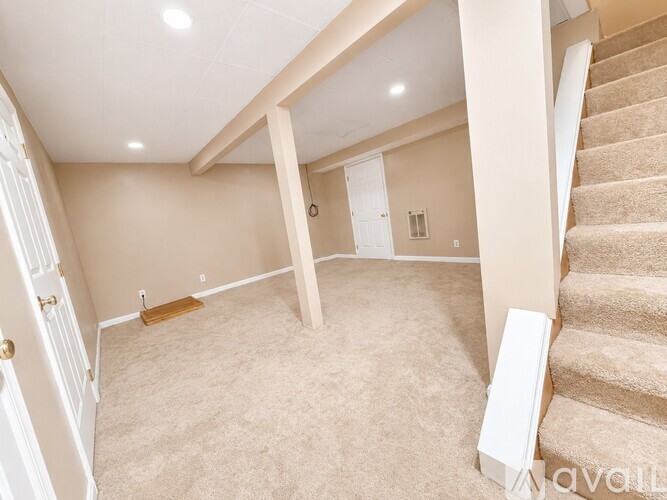A spacious room with a staircase leading to the upper level.