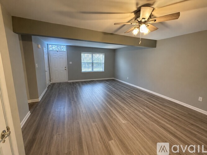 A room with a ceiling fan and wooden flooring.
