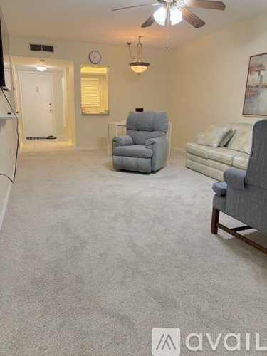 A living room with a grey carpet and furniture.