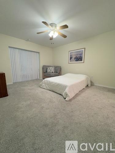 A bedroom with a bed, a ceiling fan, and a picture on the wall.