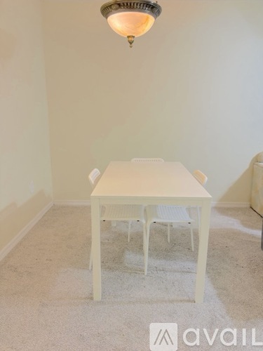 A white dining table with four chairs is in a room with a carpeted floor.