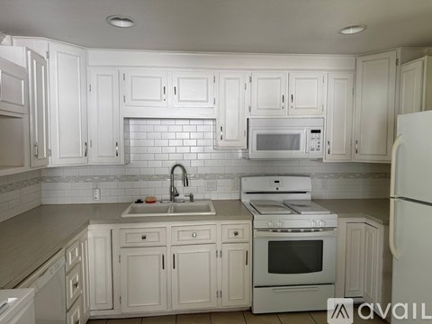 A kitchen with white cabinets and appliances.