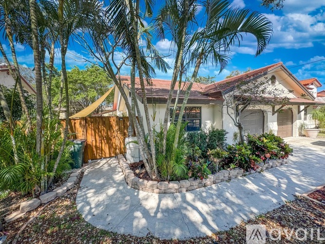 A house with a white fence and a tree in front.
