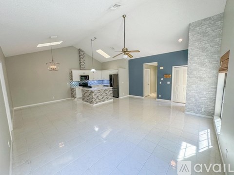 A spacious living room with a kitchen area in the background.