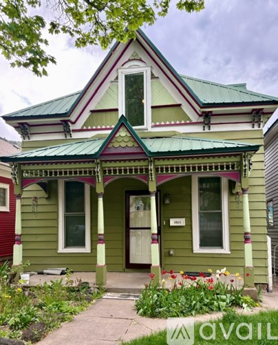A green house with a porch and a sign that says "available".