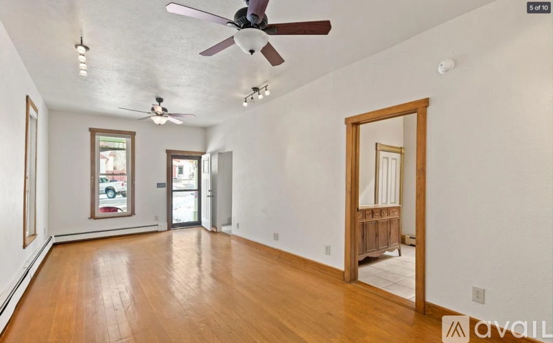 A room with a ceiling fan and wooden floors.