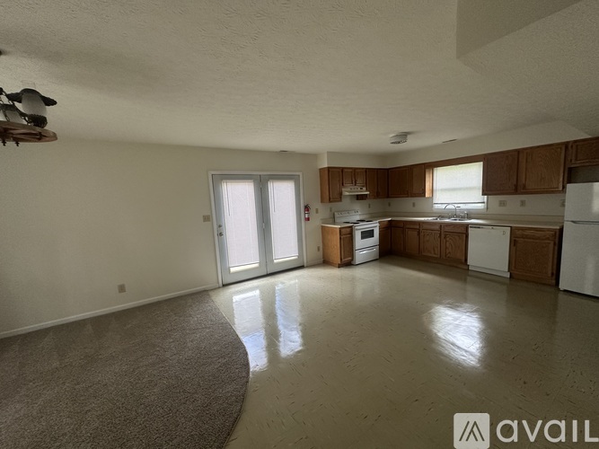 A spacious living room with a kitchen in the background.