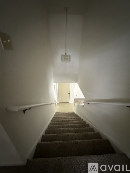 A stairway with a carpeted runner and a light hanging from the ceiling.
